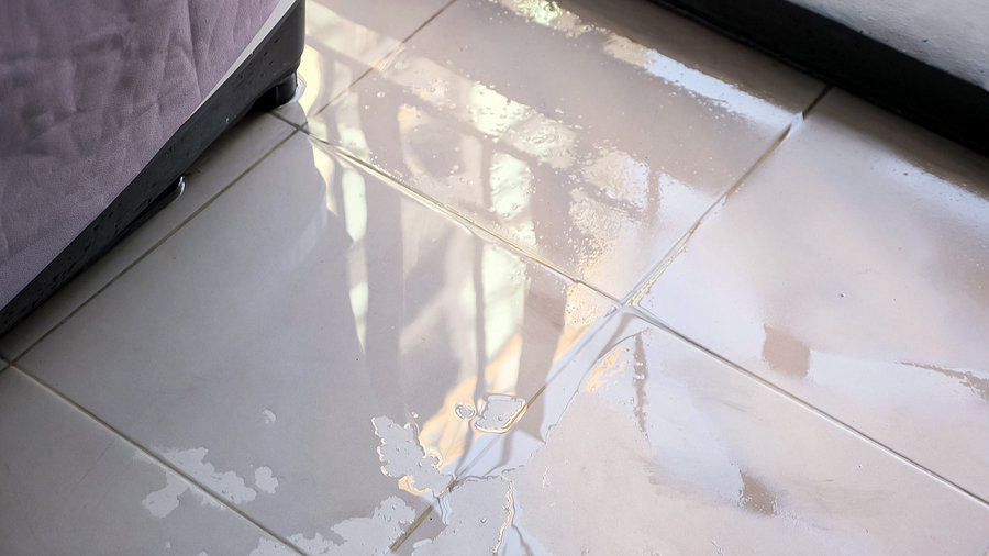 Trembling Water Puddle After Pipe Burst Covers White Tile